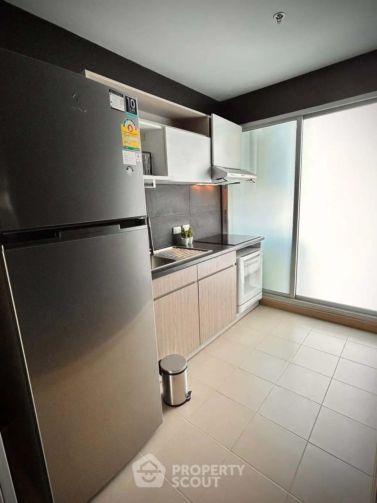 Modern kitchen with stainless steel fridge and sleek cabinetry in a bright apartment.