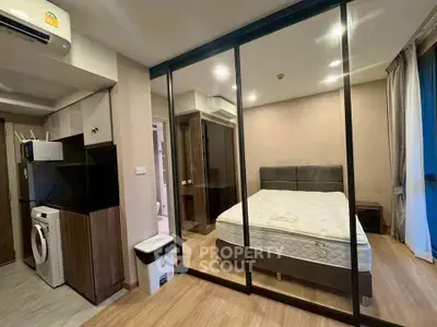 Modern studio apartment with glass partition, featuring a cozy bedroom and compact kitchen area.