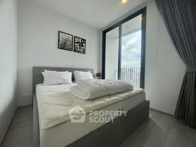 Modern bedroom with large window and city view, featuring a comfortable bed and stylish decor.