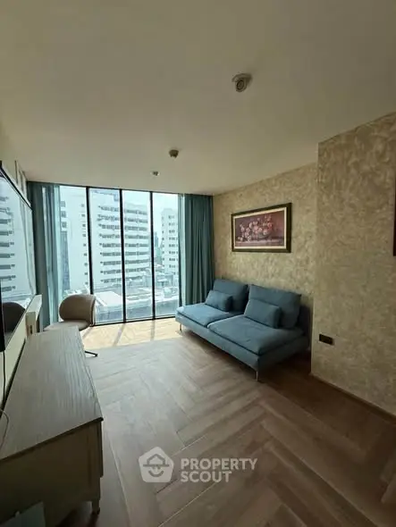 Modern living room with large windows and city view, featuring stylish furniture and elegant decor.