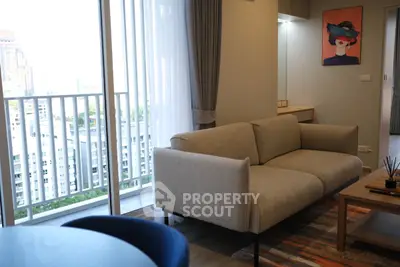 Modern living room with stylish sofa and balcony view in urban apartment.