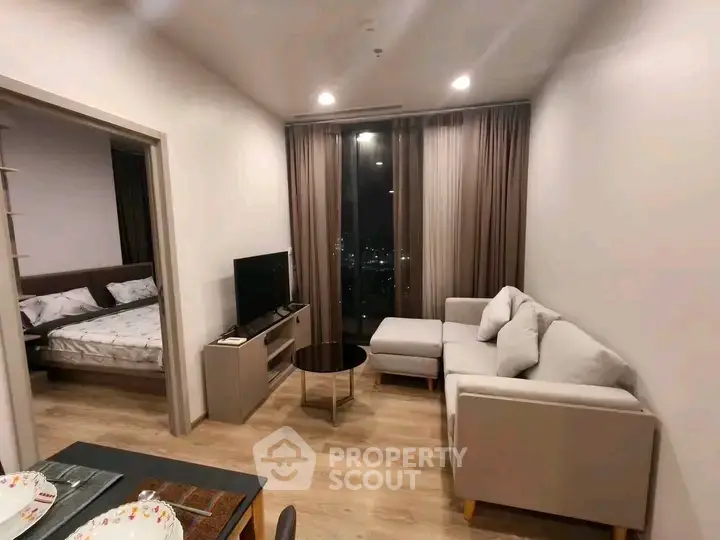 Modern living room with cozy sofa and city view, adjacent to a stylish bedroom.