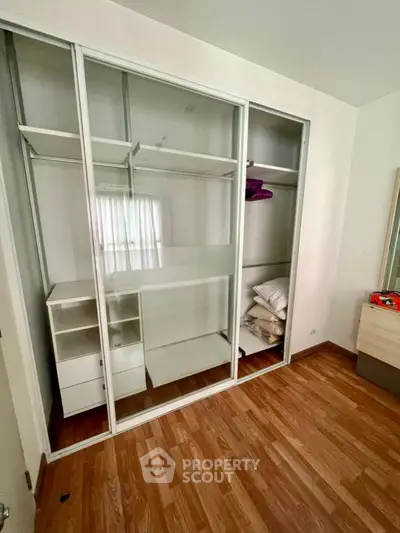 Spacious bedroom with built-in sliding door wardrobe and wooden flooring