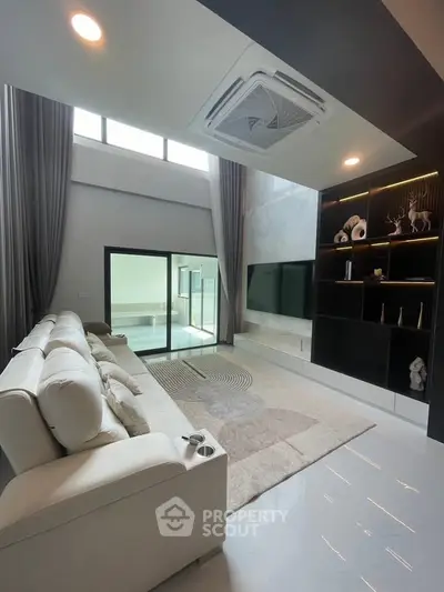 Luxurious modern living room with high ceilings, elegant decor, and large windows for natural light.