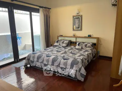 Spacious bedroom with modern decor and large windows opening to a private balcony.
