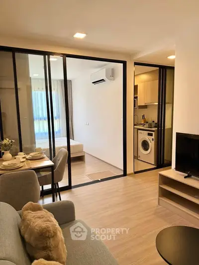 Modern apartment interior with open living area, cozy bedroom, and compact kitchen featuring a washing machine.