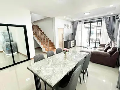 Spacious modern living room with elegant dining area and stylish staircase in a bright open-plan layout.