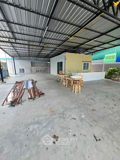 Spacious industrial-style covered outdoor area with metal roof and concrete floor, ideal for workshops or storage.