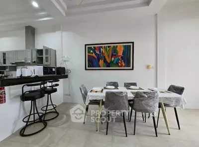 Modern dining area with stylish chairs and vibrant wall art in open kitchen layout.