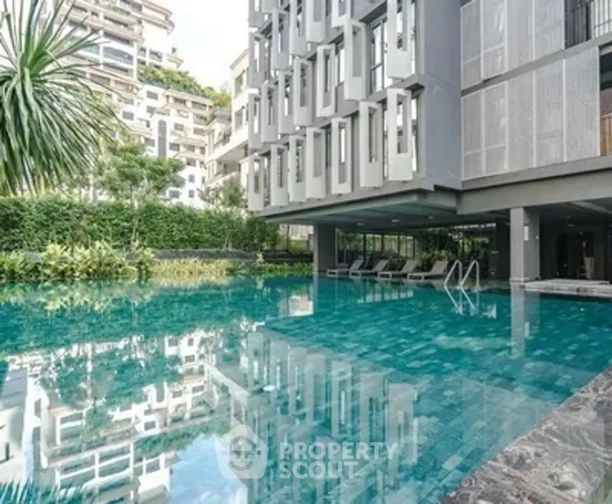 Luxurious modern apartment complex with stunning pool and lush greenery.