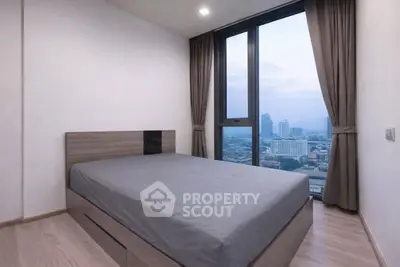 Modern bedroom with city view and large windows in high-rise apartment.