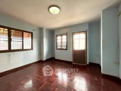Spacious empty room with wooden flooring and large windows, ideal for customization.