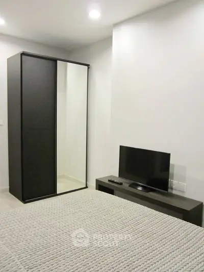 Modern bedroom with sleek wardrobe and flat-screen TV, perfect for minimalist living.