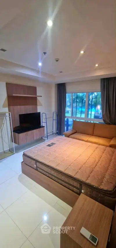 Spacious bedroom with large window and modern furnishings in a stylish apartment.