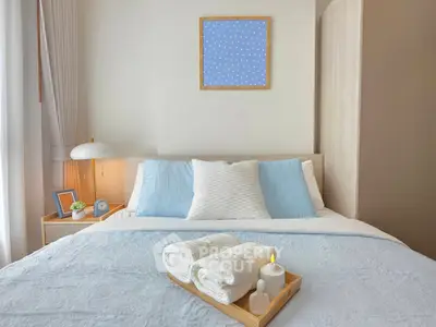 Cozy bedroom with soft blue accents and neatly arranged towels on bed, creating a serene and inviting atmosphere.