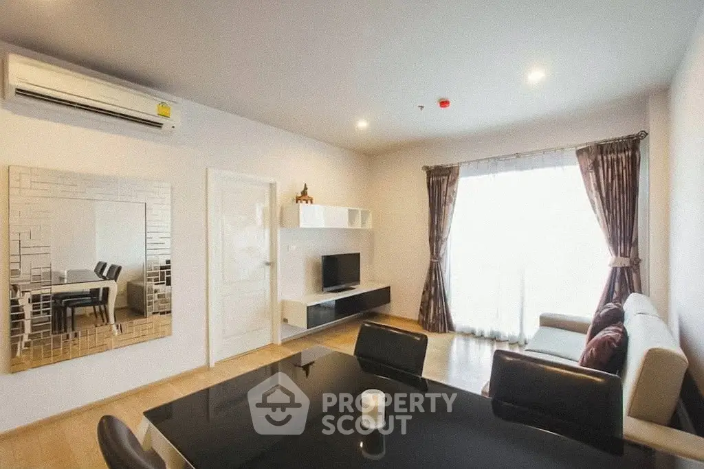Modern living room with stylish decor and natural light, featuring a sleek dining area and comfortable seating.