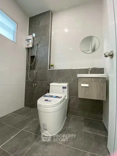 Modern bathroom with sleek design, featuring a toilet, sink, and shower area with stylish tiles.