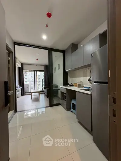 Modern apartment with sleek kitchen and spacious living area, featuring large windows for natural light.