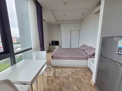 Modern studio apartment with large windows and stylish furnishings, offering a cozy and bright living space.