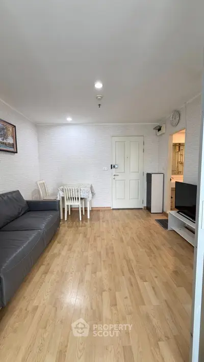 Spacious living room with wooden flooring and modern furniture in a cozy apartment.