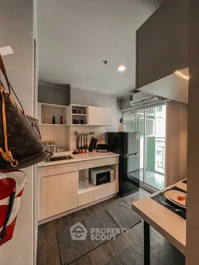 Modern kitchen with sleek cabinetry and balcony access in stylish apartment.