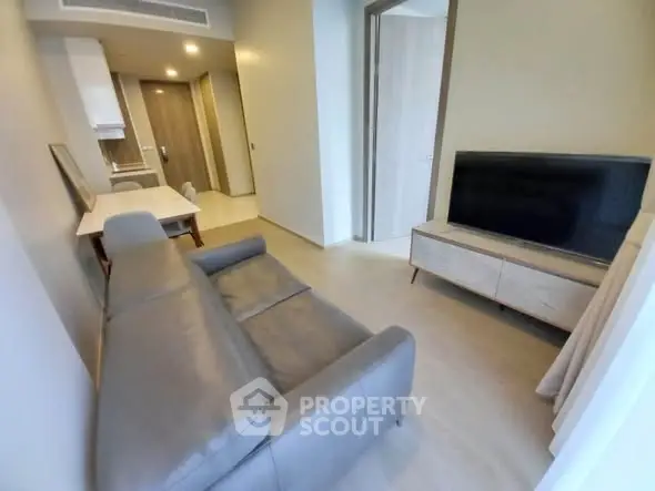 Modern living room with sleek furniture and large TV in a stylish apartment.