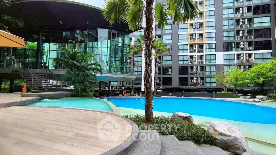 Luxurious modern apartment complex with stunning pool and lush greenery, perfect for urban living.
