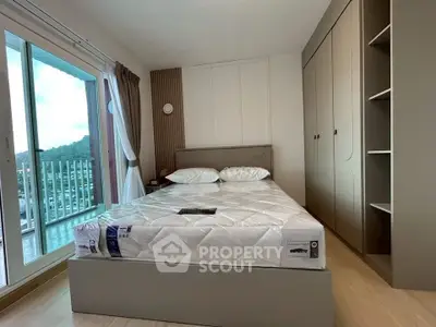 Modern bedroom with large window and scenic view, featuring a comfortable bed and ample storage space.