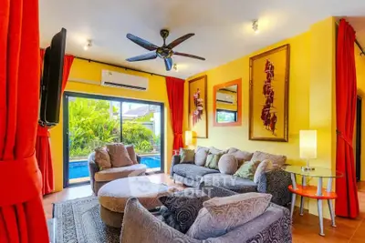 Vibrant living room with pool view, stylish furniture, and bold red curtains.