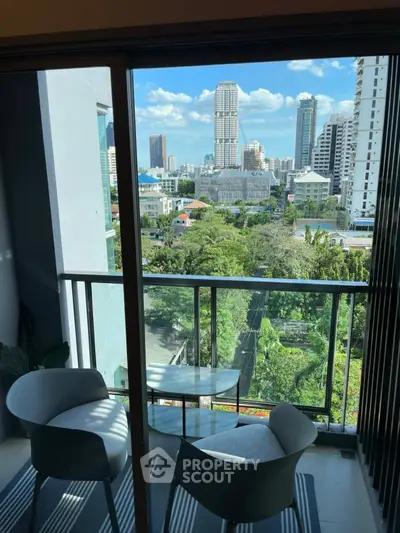 Chic urban balcony with city skyline view and cozy seating area.