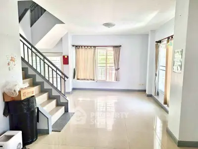 Spacious and bright living room with large windows and staircase, perfect for modern living.