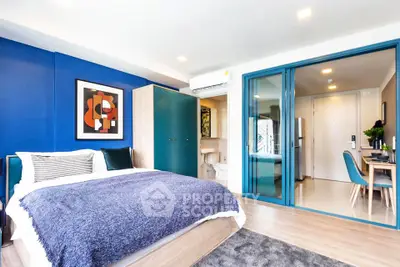 Modern bedroom with blue accents and ensuite bathroom in stylish apartment.