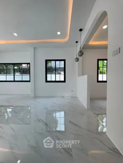 Spacious modern living room with glossy marble floors and elegant lighting.