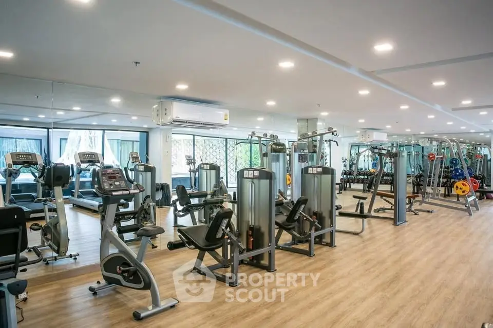 Spacious modern gym with state-of-the-art fitness equipment and large windows for natural light.