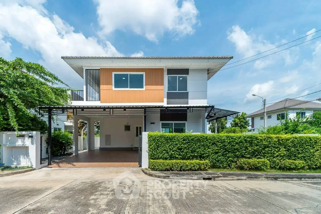 Modern two-story house with spacious driveway and lush greenery.