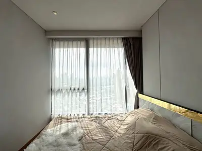 Cozy bedroom with large window offering stunning city view and elegant decor.