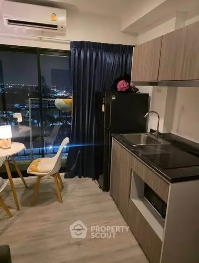 Modern kitchen with city view, sleek cabinetry, and cozy dining area in urban apartment.