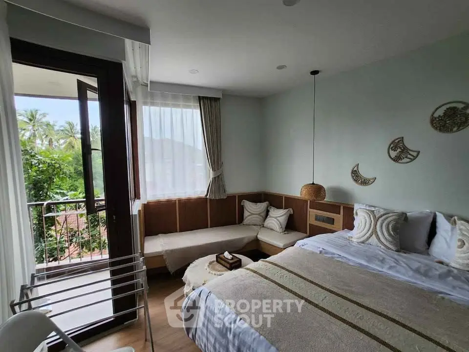 Cozy bedroom with balcony and nature view, featuring elegant decor and ample natural light.
