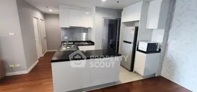 Modern kitchen with sleek white cabinets and black countertops, featuring a gas stove and stainless steel appliances.