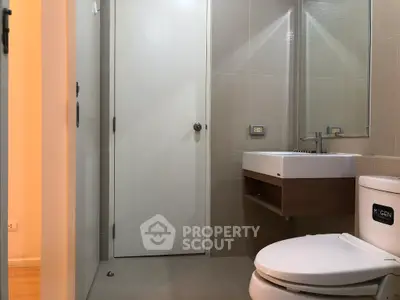 Modern bathroom with sleek fixtures and neutral tones, featuring a stylish sink and toilet.