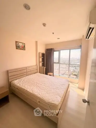 Bright and cozy bedroom with large window offering stunning city views, perfect for relaxation and comfort.