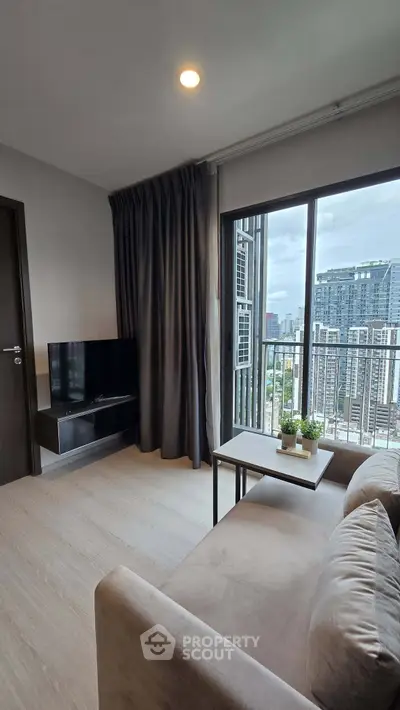 Modern living room with city view, featuring cozy sofa and sleek TV setup.