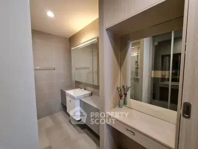 Modern bathroom with sleek vanity and large mirror in a stylish apartment.