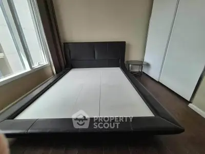 Spacious bedroom with modern bed frame and large window for natural light.