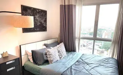 Cozy bedroom with large window offering city views, modern decor, and stylish bedding.