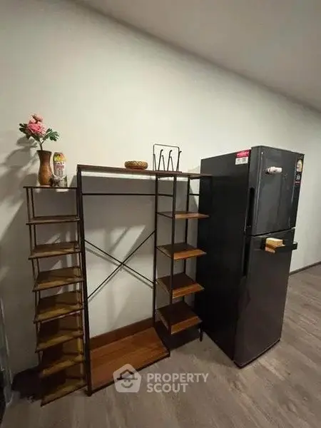 Modern kitchen corner with sleek black fridge and stylish shelving unit.