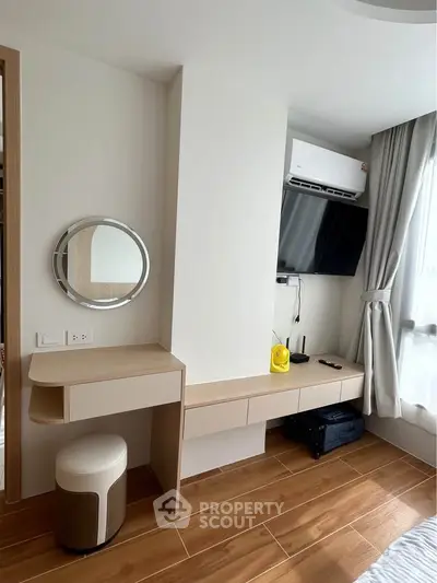 Modern bedroom with sleek wooden flooring, wall-mounted TV, and stylish vanity desk.