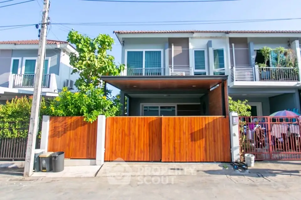 Modern townhouse with wooden gate and balcony in a sunny neighborhood
