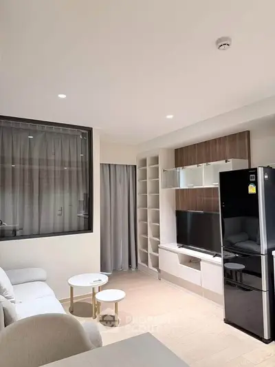 Modern living room with sleek furniture and built-in shelving, featuring a large TV and stylish decor.