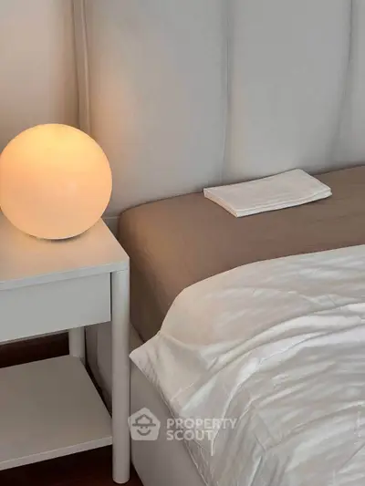 Cozy bedroom corner with modern lamp and soft bedding